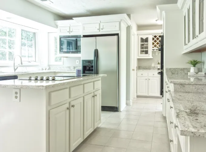 Kitchen with tile floor, white cabinets, and granite countertops.