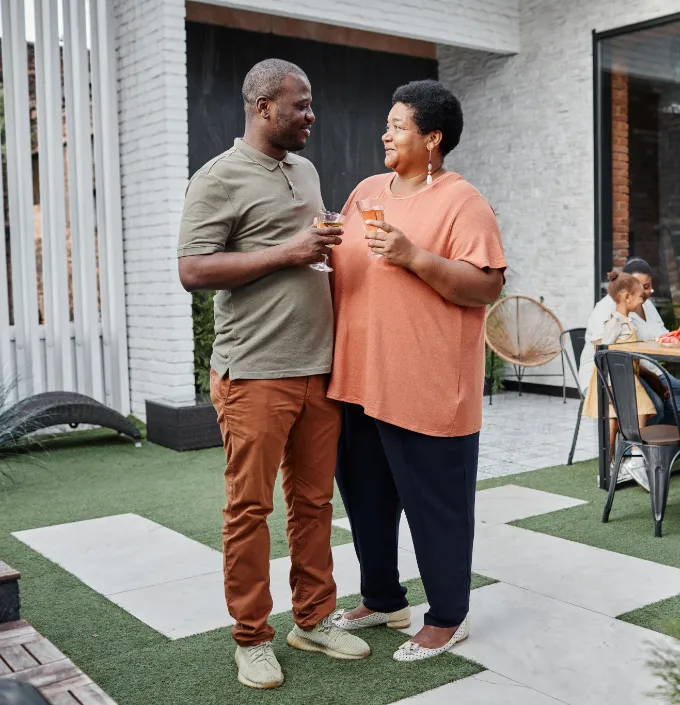African American man and woman standing together with drinks in backyard.