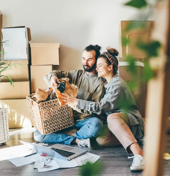 Couple sitting on floor unpacking belongings from moving.